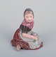 Royal Copenhagen, regional figurine of a girl from Faroe Islands. Overglaze. 
Dressed in regional costume and holding a bouquet of flowers.