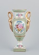 Limoges/Sevres, France. Porcelain vase on a pedestal, handles shaped like swans. 
Hand-decorated with polychrome floral motifs.