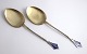 Aug. Thomas. 
Silver-gilt 
serving parts 
with enamel 
(830). A pair. 
Length 25 cm. 
Produced 1903.