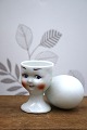 Old egg cup from the 1930s in porcelain with a painted funny face. Height: 6.5cm.