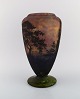 Daum Nancy, France. Large vase in mouth blown art glass decorated with landscape with trees. Approx. 1920.