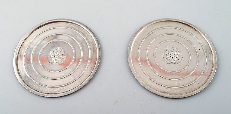 Georg Jensen: Twocoasters of sterling silver. Inside chased with a bunch of 
grapes.