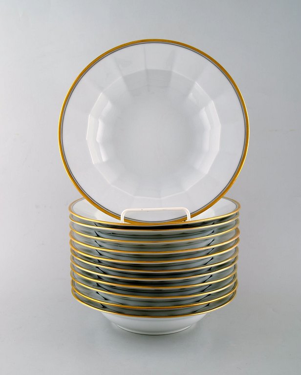 Royal Copenhagen. Twelve deep plates in porcelain with gold border.
