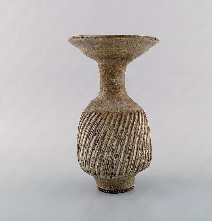 Lucie Rie (f. 1902, d. 1995, østrigsk-født britisk keramiker. Stor modernistisk 
unika vase i glaseret keramik / stentøj. Smuk glasur i lyse jordnuancer. Rillet 
korpus. Trumpet formet munding. Eget værksted, ca. 1970.
