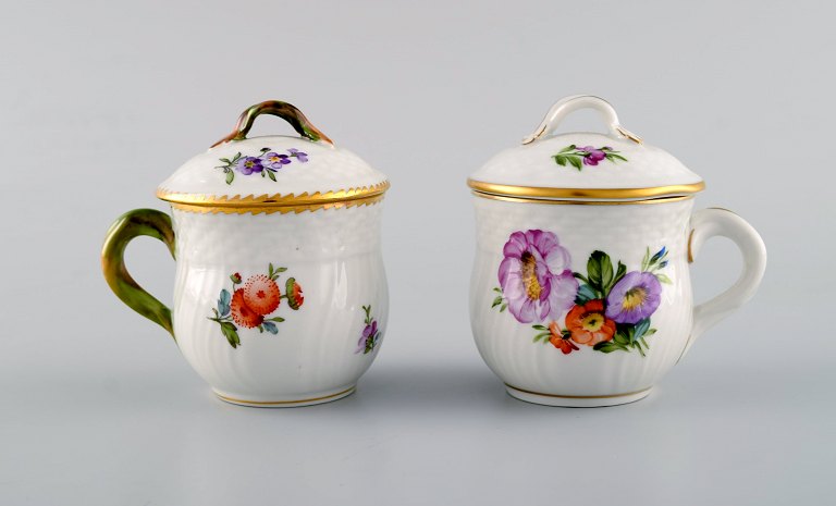 Two Royal Copenhagen Saxon Flower porcelain cream cups with floral motifs.
