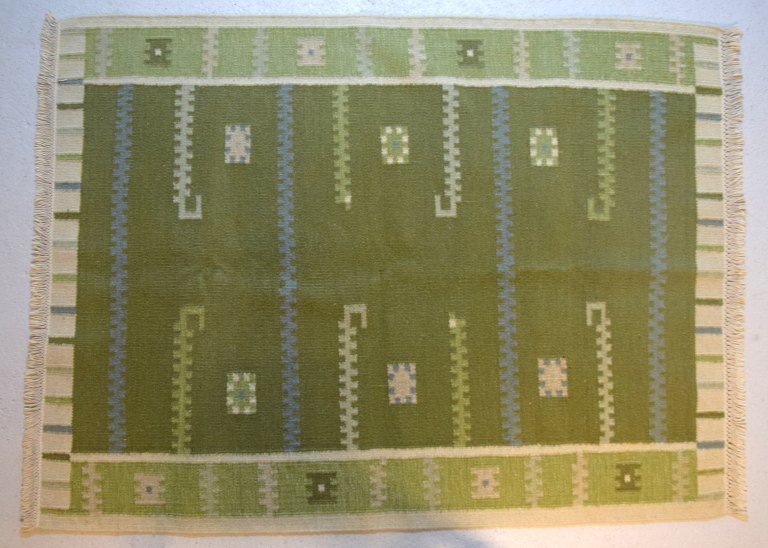 Svensk tekstildesigner. Håndvævet RÖLAKAN tæppe med geometriske felter i grønne, 
blå og creme nuancer. Midt 1900-tallet.
