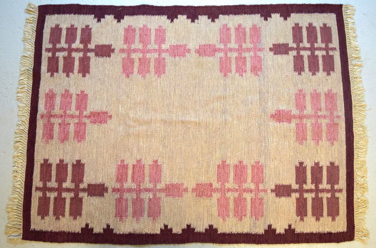 Svensk tekstildesigner. Håndvævet RÖLAKAN tæppe med geometriske felter i lilla, 
lyserøde og creme nuancer. Midt 1900-tallet.
