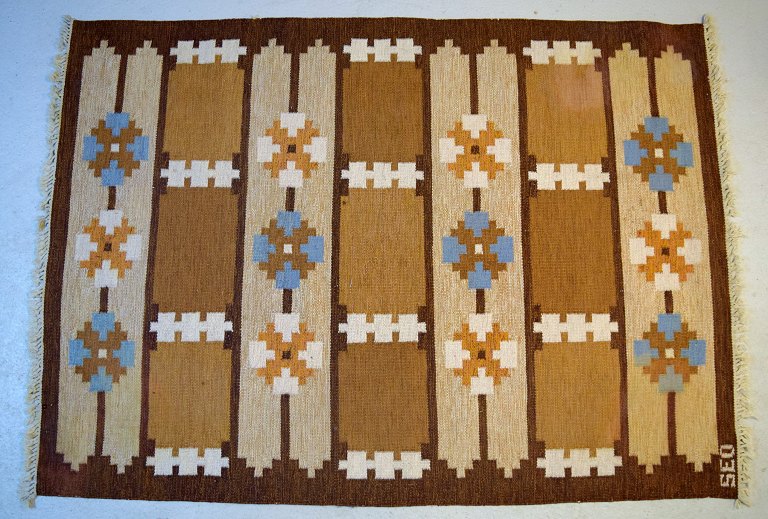 Swedish textile designer. Large hand-woven RÖLAKAN rug in pure wool with 
geometric fields and clean lines in brown, blue and sand-colored shades. 
Mid-20th century.
