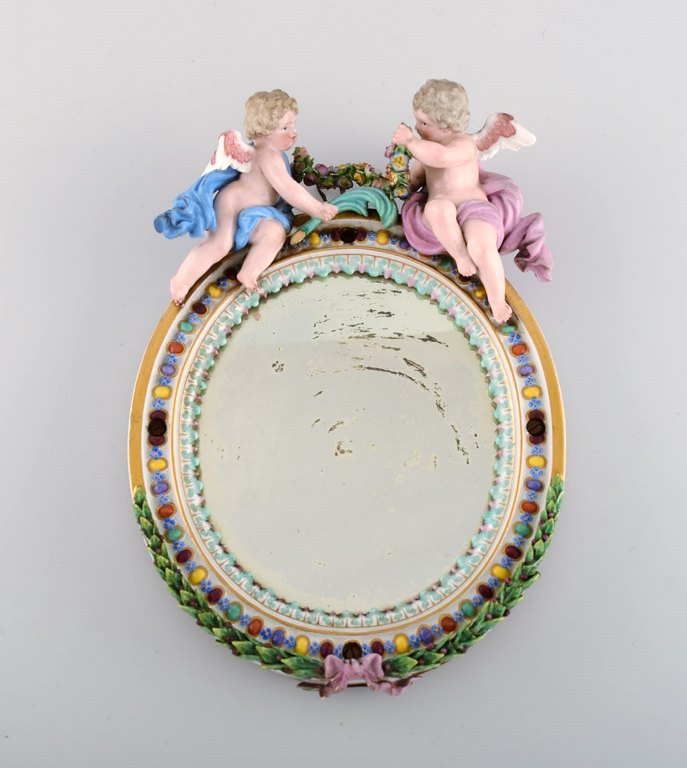 Antique Meissen porcelain mirror with original glass. Decorated with angels and 
repousse flowers. 19th century.
