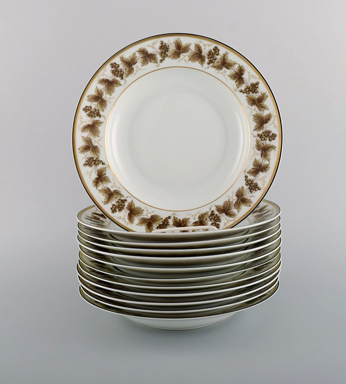 12 Limoges dybe tallerkener i porcelæn med håndmalede vindrueranker og 
gulddekoration. 1930/40