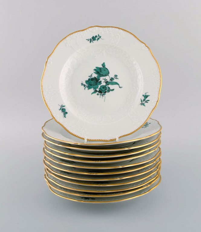Tolv antikke Meissen tallerkener i porcelæn med håndmalede blomster og guldkant. 
Ca. 1900.
