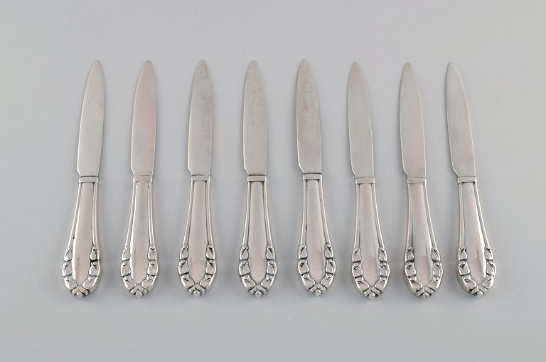 Otte tidlige Georg Jensen Liljekonval frugt / smørknive i helsølv (830). Dateret 
1915-1930.
