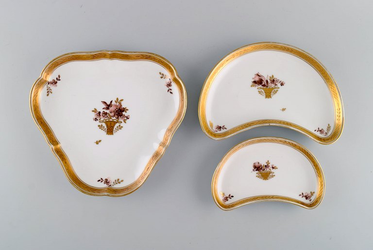 Tre Royal Copenhagen Guldkurv fade i porcelæn med blomster og gulddekoration. 
Tidligt 1900-tallet.
