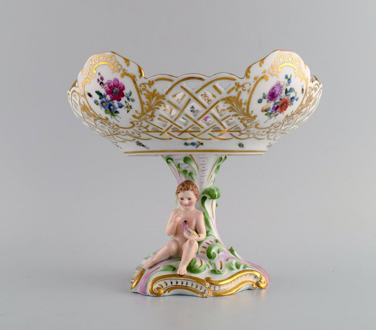 Early and rare Royal Copenhagen compote in openwork porcelain with hand-painted 
flowers and gold decoration. Foot modeled with Putto holding bird. Museum 
quality. Early 19th century.
