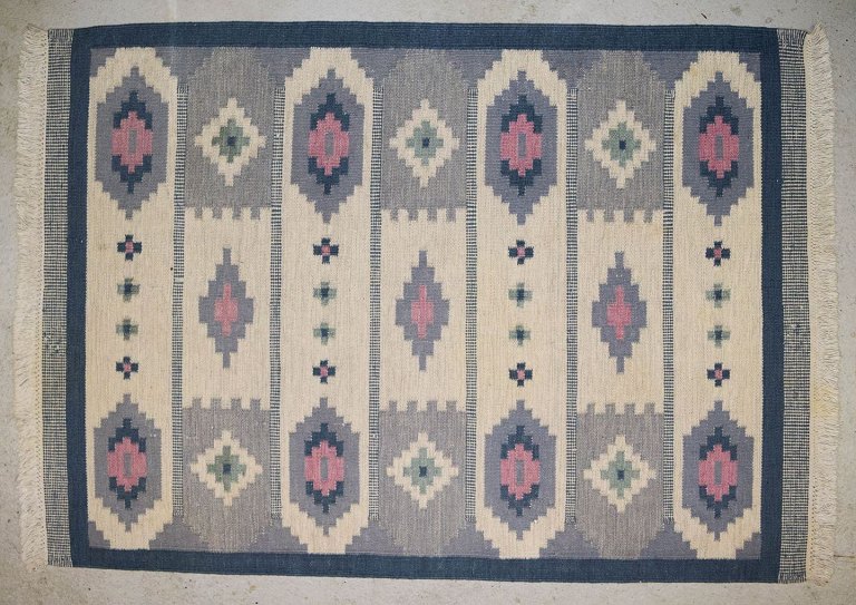 Swedish handwoven wool rug with fringes in the "Rölakan" technique.
Geometric shapes in light blue, dark blue, and pink on a white background.