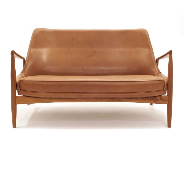 Ib Kofod-Larsen zwei Personen Sofa aus Teak bezogen mit patiniertem Leder. 
Design aus dem Jahre 1957. L: 138cm