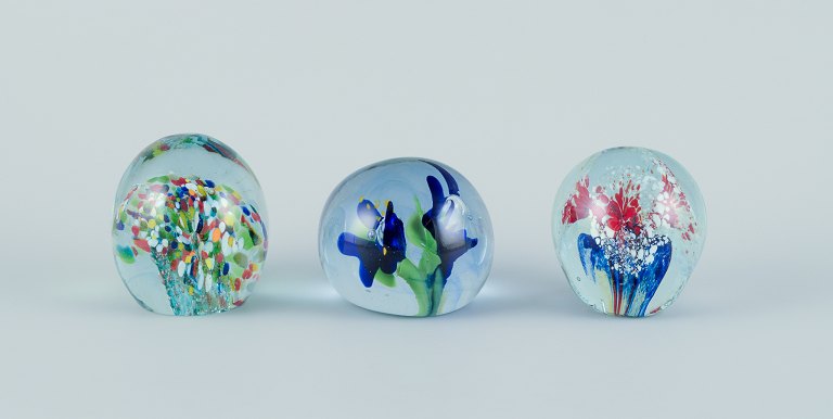 Scandinavian glass artist. Set of three paperweights in art glass. Flower motifs 
and more embedded in the glass. Handmade.
