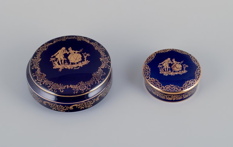 Limoges, France. Two round covered jars in porcelain decorated with 22-karat 
gold leaf and beautiful royal blue glaze. Scène galante.