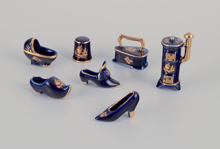 Limoges, France. Seven pieces of porcelain miniatures, decorated with 22-karat 
gold leaf and a beautiful royal blue glaze. Scène galante.