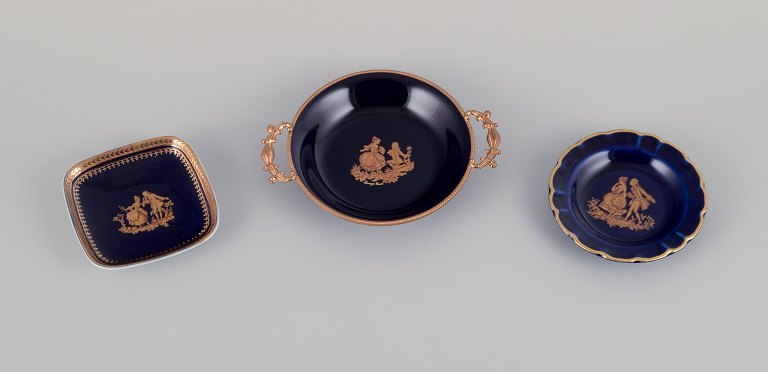 Limoges, France. Three small porcelain bowls decorated with 22-karat gold leaf 
and beautiful royal blue glaze. Scène galante.