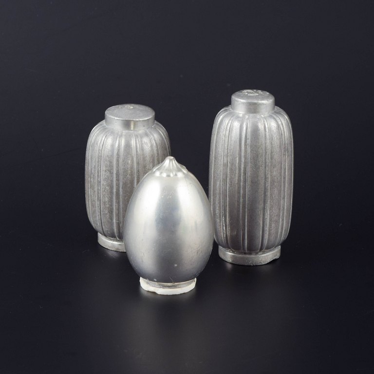 Just Andersen, DenmarkSet of three salt and pepper shakers in pewter, two with ribbed bodies and one with a smooth, egg-shaped form.